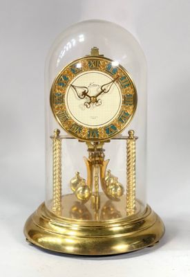 une horloge en or sous un dôme de verre sur une table