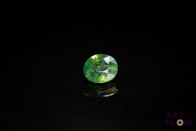 a close up of a green and white diamond on a black surface