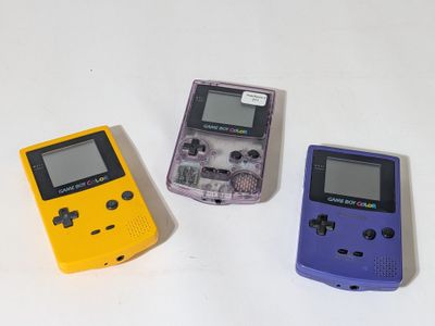 three nintendo game consoles sitting side by side on a white surface