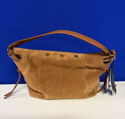 un sac à main marron posé sur une table près d'un mur bleu