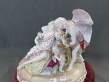 figurine en porcelaine représentant un couple assis sur un coussin rouge, tenant un parapluie