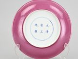 pink and white plate with chinese writing on it on a stand