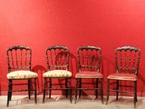 four chairs are lined up against a red wall in a room