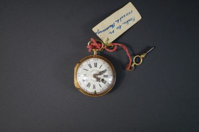 une petite montre de poche en or à laquelle est attachée une étiquette