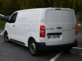 a white van parked in a parking lot with trees in the background