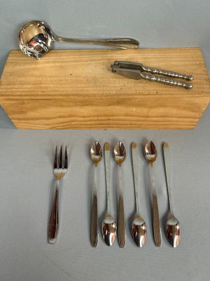 plusieurs cuillères, fourchettes et un repose-cuillère posés sur un plateau en bois