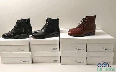 trois paires de bottes sont posées sur des cartons, sur une surface blanche