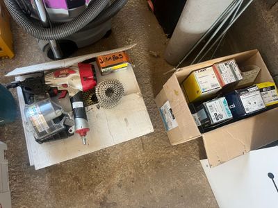 une boîte contenant divers objets, posée par terre à côté d'un aspirateur