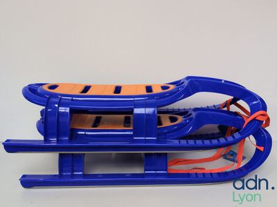 a blue sled with orange handles on a white table