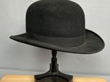 black hat on a wooden stand on a gray background
