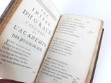 someone is holding an open book in their hand on a white surface