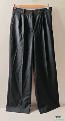 un pantalon en cuir noir suspendu à un cintre devant un mur blanc