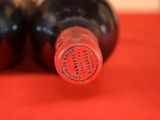 two bottles of wine sitting on a red cloth