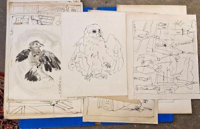 une pile de dessins posée sur une table, à côté d'une pile de papiers