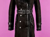 un manteau noir à col de fourrure posé sur un présentoir pour mannequin