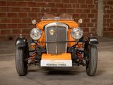 an orange car that is parked in front of a brick wall