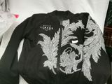 black jacket with white embroidery on it sitting on a white chair