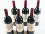 six bottles of wine are lined up in a row on a white surface