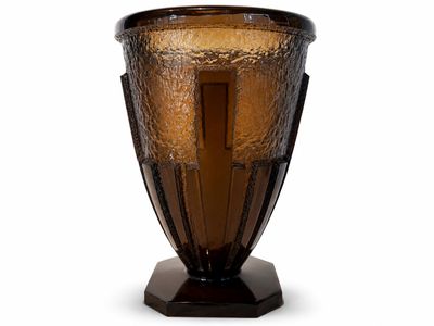 un vase en verre brun avec un socle noir sur fond blanc
