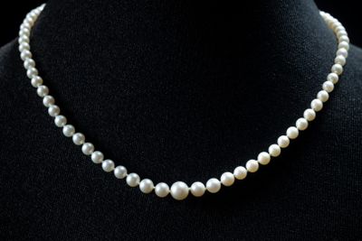 a close up of a white pearl necklace on a mannequin