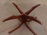 a wooden table with four legs on a cement floor