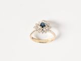 a close up of a gold ring with a blue sapphire and white diamonds