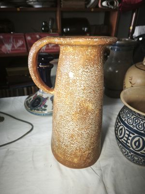 a brown vase sitting on a table with a white table cloth