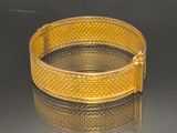 bracelet plaqué or sur une surface réfléchissante avec un fond noir