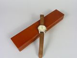 une croix en bois sur laquelle est posée une montre, posée sur une surface blanche