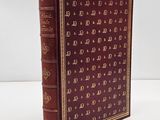 a red book with gold letters on it sitting on a white surface
