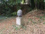 a statue of a man sitting on a pedestal in the middle of a field
