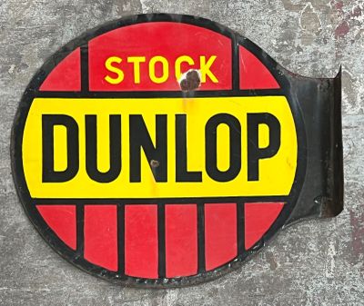 a red and yellow sign that says stock dunlop on the side of a building