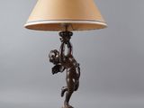 a bronze lamp with a cupid holding a flower on it ' s arm