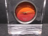 a glass clock with a red face on a black surface
