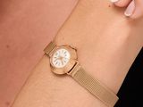 une femme portant une montre en or au poignet, sur fond noir