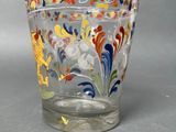 a glass cup with colorful designs on it on a table