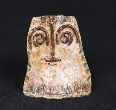 un gros plan d'une sculpture en céramique représentant un visage sur fond noir