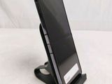 a black cell phone on a stand on a white surface