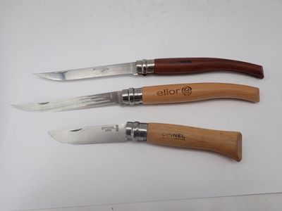 trois types différents de couteaux à manche en bois posés sur une surface blanche
