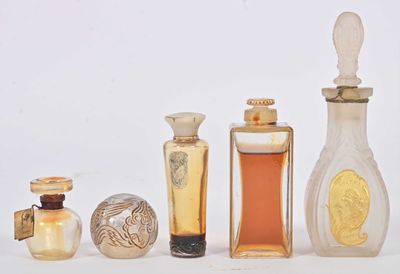 cinq flacons de parfum posés les uns à côté des autres sur une surface blanche