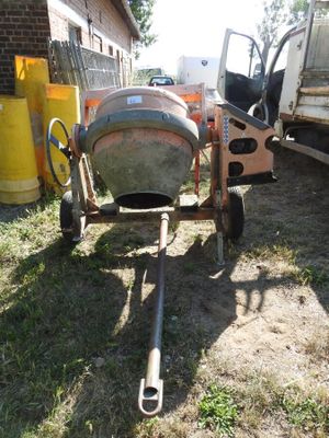a cement mixer sitting in the grass next to a truck