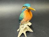 a figurine of a bird sitting on top of a leaf