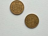 two gold coins sitting on top of a white surface next to each other
