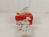 pair of white baby shoes sitting on top of a red box