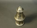 a small metal pepper shaker sitting on a table