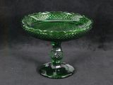 un bol en verre vert posé sur un socle, sur fond noir