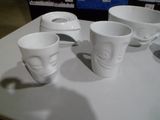 quatre tasses ornées de visages, posées sur une table