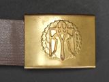 gold belt buckle with a cross on it on a black surface