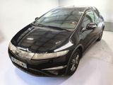 the black honda civic is parked in a white room