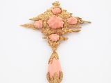 un pendentif-broche rose et doré orné d'un motif floral